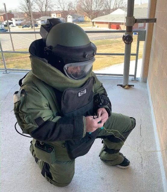 Cody Rose kneeling in a bomb disposal suit during render-safe training.